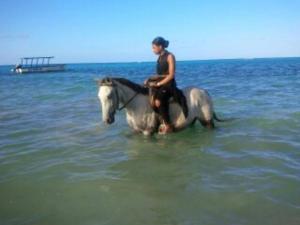 a woman riding a horse in the ocean at JUS4U-Apt-3 The Home Away From Villa in Ocho Rios