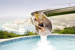 a group of people riding a water slide around a swimming pool at JUS4U-Apt-3 The Home Away From Villa in Ocho Rios