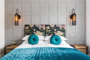 a bedroom with a large bed with blue pillows at L-Spa Boutique Apartments in Leamington Spa