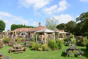 um edifício com mesas de piquenique e um gazebo em Woodcocks, Lincoln by Marston's Inns em Lincoln