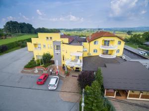 a yellow house with a car parked in a parking lot at Hotel Orion in Ivanec