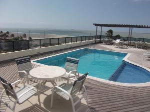 einen Pool mit einem Tisch und Stühlen am Strand in der Unterkunft Calhau Praia Hotel in São Luís