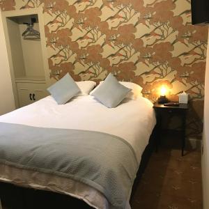 una camera da letto con un letto e carta da parati floreale di The Victoria Inn Blythswood Snug a Falkirk