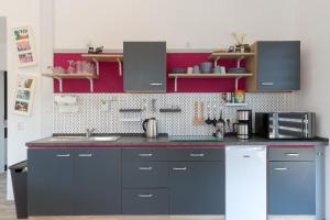 una cocina con armarios grises y una pared roja en Clara Hills, en Eberswalde-Finow