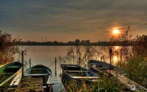 two boats are docked on a lake at sunset at Clara Hills in Eberswalde-Finow