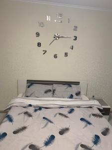 1 dormitorio con 1 cama con reloj en la pared en Apartments on Priportovaya,35, en Cherkasy