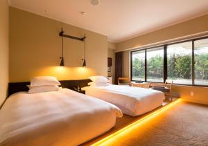 a bedroom with two beds and a large window at Royal Park Hotel Takamatsu in Takamatsu