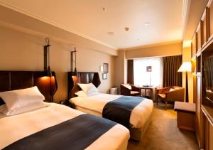 a hotel room with two beds and a desk at Royal Park Hotel Takamatsu in Takamatsu