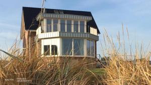 a house sitting on top of a hill with tall grass at Luxuswohnung Pazifik WESER WELLNESS WHIRLPOOL in Brake
