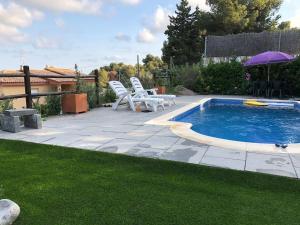 a swimming pool with two chairs and an umbrella at Casa Bella Vista en montaña con vistas al mar y piscina privada in Cunit