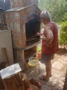 un hombre está poniendo algo en un horno al aire libre en Apartments L.Z. en Starigrad-Paklenica