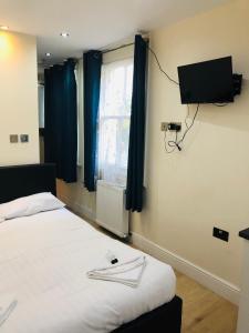1 dormitorio con 1 cama y TV en la pared en Kensington and Chelsea Apartment, en Londres