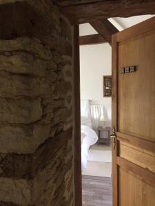 una porta aperta su una camera da letto con parete in pietra di L'ancien Presbytère d'Ardevon ad Ardevon