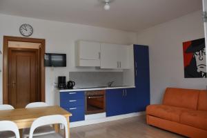 cocina y sala de estar con armarios azules y mesa en Villa Dina, en Riva del Garda