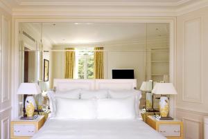 a bedroom with a large white bed with mirrors at Grand-Hôtel du Cap-Ferrat, A Four Seasons Hotel in Saint-Jean-Cap-Ferrat