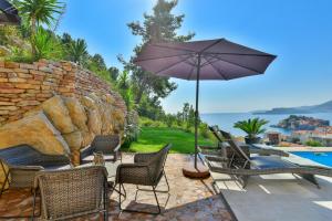 a patio with chairs and an umbrella and a pool at Lux Apartment Luna in Sveti Stefan