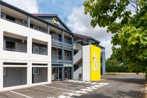 un edificio de oficinas con una fachada amarilla y blanca en B&B HOTEL Angers 1 Beaucouzé, en Beaucouzé