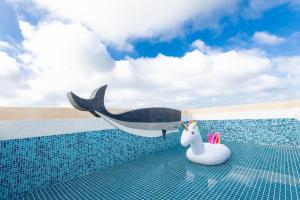 uma baleia de brinquedo e um unicórnio de brinquedo ao lado de uma piscina em Kiwi Villa em Magong