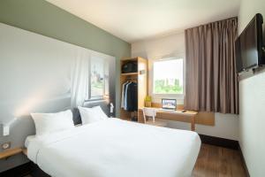 a hotel room with a large white bed and a desk at B&B HOTEL Creil Chantilly in Creil