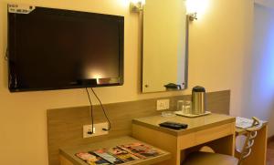 Habitación con TV en la pared y mesa. en Rama Krishna Hotel en Bombay