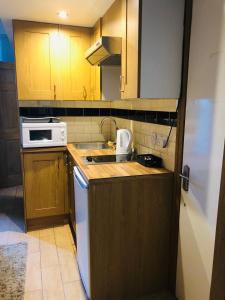 una pequeña cocina con armarios de madera y electrodomésticos blancos en Kensington and Chelsea Apartment, en Londres
