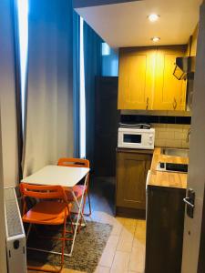 una pequeña cocina con mesa y sillas naranjas en Kensington and Chelsea Apartment, en Londres
