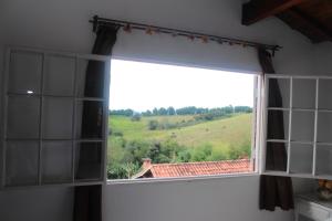 a window with a view of a green field at Pousada Calu in Cunha
