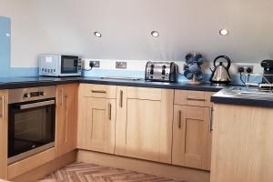 a kitchen with wooden cabinets and blue counter tops at The Old School Loft in Blidworth