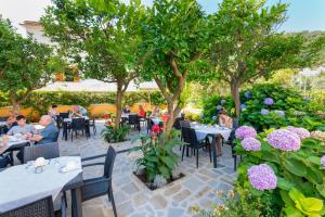 a group of people sitting at tables in a garden at Hotel Leone in Sorrento