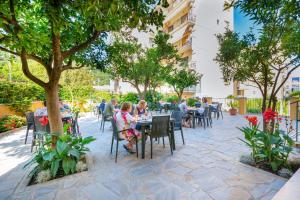 people sitting at tables in a courtyard with trees at Hotel Leone in Sorrento