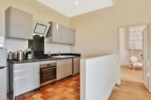 a kitchen with white cabinets and a black refrigerator at La Maison des Consuls in Périgueux