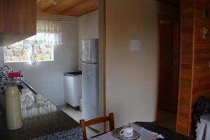 Apartamento Serrano في ساو جواكيم: مطبخ مع ثلاجة وطاولة في الغرفة