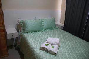 a bed with a green comforter and towels on it at Apartamento Serrano in São Joaquim