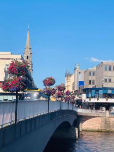 eine Brücke über einen Fluss mit Blumen auf Bäumen in der Unterkunft Scardroy Homes Apartment Inverness in Inverness