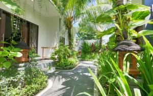een tuin met palmbomen en een loopbrug bij Palm Bamboo Hotel in Nusa Dua