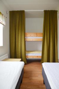 two beds in a room with green curtains at Apelvikstrand in Varberg
