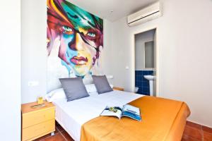 a bedroom with a bed, a desk and a painting on the wall at Ryans La Marina in Ibiza Town