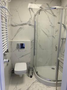 a white bathroom with a shower and a toilet at Pokoj Pod Żaglami in Gdynia +4 photos
