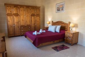 a bedroom with a bed with wooden furniture and cabinets at Acomodation House Kavarna in Xagħra