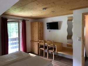 a bedroom with a bed and a desk and a tv at Pension Hofeck in Bernau im Schwarzwald