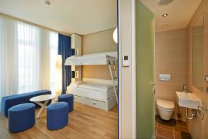 a small room with a bunk bed and a bathroom at H2 Hotel München Messe in Munich +36 photos