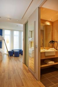 uma casa de banho com um espelho grande e um lavatório em H2 Hotel München Messe em Munique