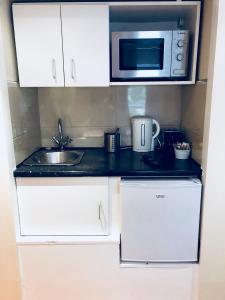 a kitchen with a microwave, sink, and dishwasher at Knaresborough Boutique Apartments in London