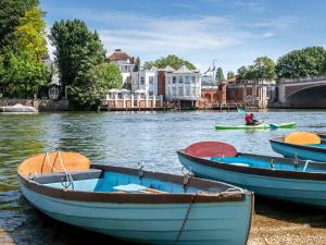 a group of boats on a river with a person in a canoe at The Mitre, Hampton Court in Kingston upon Thames