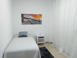 a white bedroom with a bed and a table at LUMINOSO, AMPLIO Y FRESCO PISO EN SANTACRUZ DE TENERIFE in Santa Cruz de Tenerife