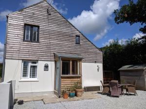 a small white house with two chairs and a table at Helford Cottage in Gweek