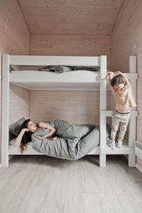 a woman and a child are laying on the bottom bunk at 333 CAMPING PARK in Silakrogs