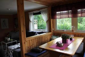 Habitación con mesa de madera y 2 ventanas. en Naturnära STUGA ULLARED en Ullared