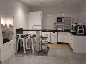 a kitchen with white cabinets and stools in it at Hostal Canton Plaza in Hospital de Órbigo