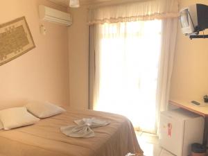Vyalle Hotel في ماشادينهو: غرفة نوم بسرير مع نافذة كبيرة